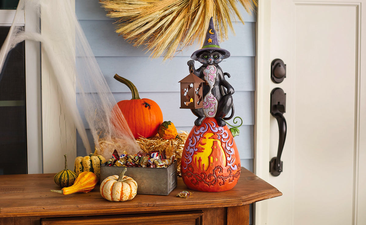 A Heartwood Creek Halloween cat statue surrounded by real pumpkins greats you at the door.